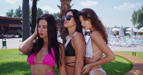 Adorables femmes en maillot de bain posant près de la piscine