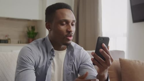 Man Video Calling Using Smartphone While Sitting on Couch