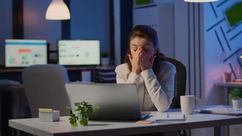 Tired Woman Working Late in Office at Laptop