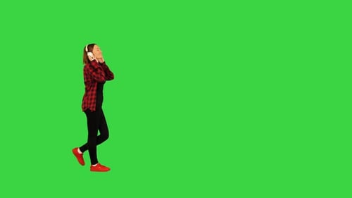 Young Girl Walks with Headphones on a Green Screen Chroma Key