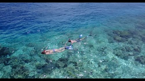 Two lovers engaged on perfect coastline beach lifestyle by shallow ocean and white sand background o