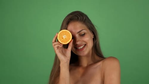 Foto de estudio de una hermosa mujer feliz sonriendo sosteniendo la mitad de una naranja 1080p