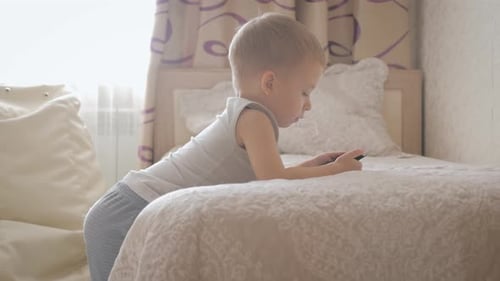 Young Child Playing on Smartphone in Bedroom