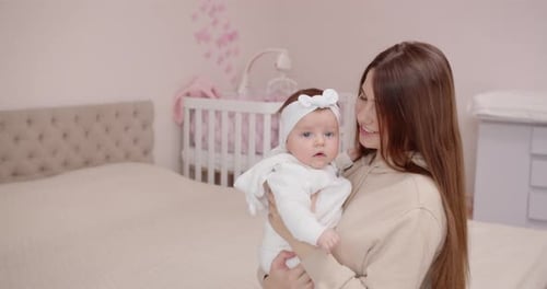 Happy Young Mother Playing With Baby Holding Her In Her Arms