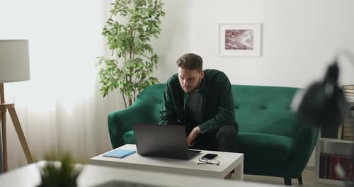 Man Using Laptop on Couch in Living Room