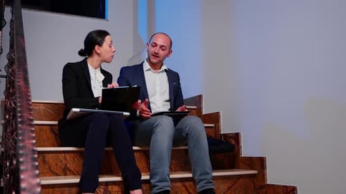 Two Business People working on Tablets on Stairs
