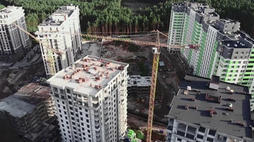Drone flying over construction site with crane and builders working on unfinished building