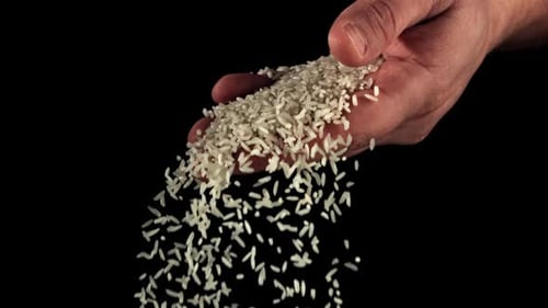 A Handful of Uncooked Rice Falls From a Man's Hand