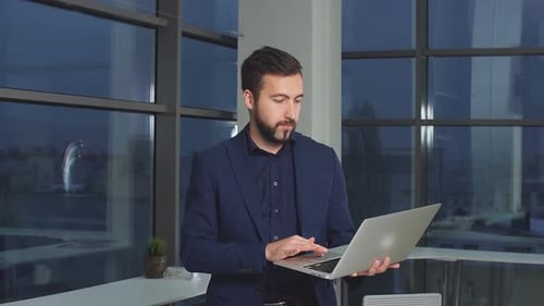 Portrait of Businessman in Office with Laptop Computer.