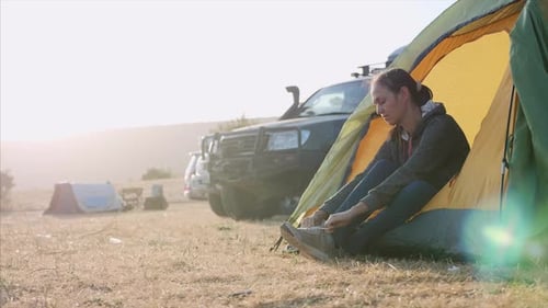 Young Woman Is Put on a Shoes Near Tourist Tent in Expedition Camp and Goes Away
