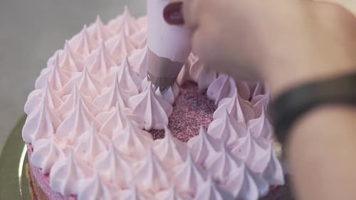 Woman Finishes Filling Top of Cake with White Air Cream