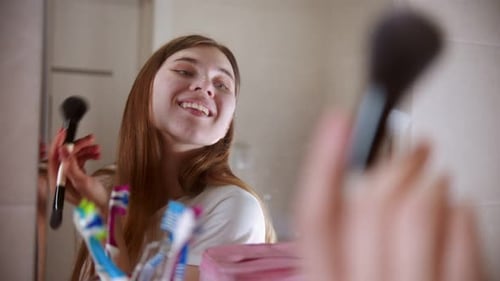 Young Woman Applying Makeup in Bathroom Mirror