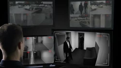 Opérateur de sécurité masculin regardant les caméras de surveillance, transaction commerciale illégale
