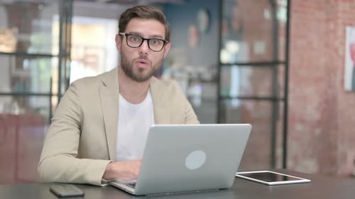 Junger Mann mit Laptop fühlt sich schockiert