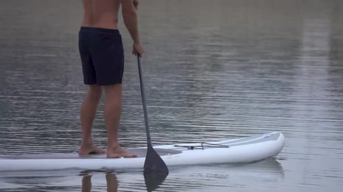 Extreme close up detail view of a man paddling his SUP stand-up paddleboard.