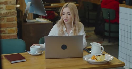Portrait Young Woman Using Laptop in Coworking Space or Cafe and Drinking Tea