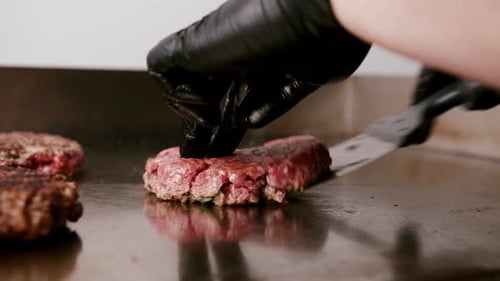 Close up view of rotating burger patty in burger bar kitchen. Meat round patty fried in the kitchen.