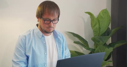 Geschäftsmann in Brille mit Laptop, der Kaffee oder Tee im Büro trinkt. Unternehmen, Leute