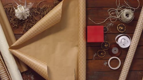 Hands of Woman Wrapping Christmas Present into Craft Paper