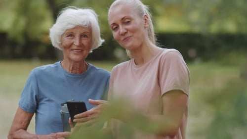 Woman Showing Smartphone to Senior Woman in Park