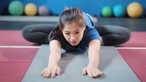 Flexible Woman Stretching on Yoga Mat in Gym