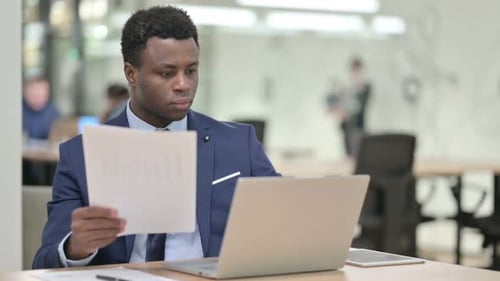 Professional Man Analyzing Documents in Modern Office