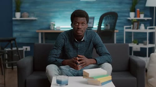 Young Man Speaking from Couch at Home