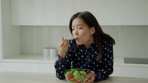 Young Woman Enjoying Salad at Kitchen Counter