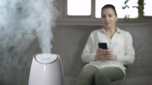 Woman Using Phone with Humidifier in Living Room