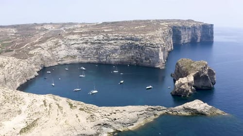 Boats and yachts anchored in a hidden Dwerja bay,Malta,cliffs,aerial.