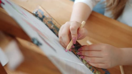 Close-up of Girl's Hand Coloring Picture Using Colored Pencils Working Alone