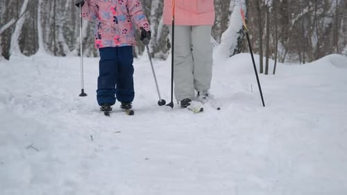 Kleines Mädchen mit Mutter beim Skifahren im Winterwald