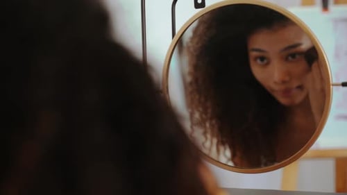 Woman Applies Makeup in Mirror at Home