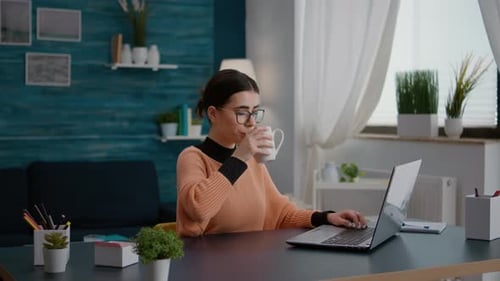 Studentin tippt auf Laptop, um Remote-Schularbeit zu erledigen