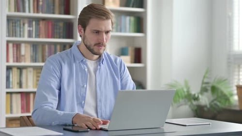 Frustrated Man Working On Laptop At Desk