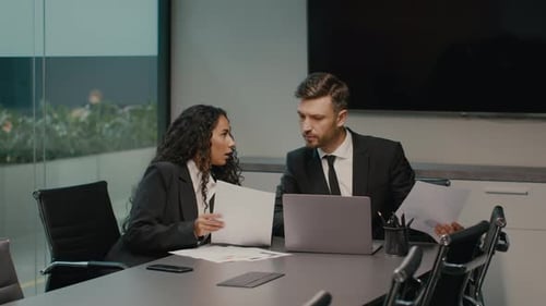Female Employee Showing Papers To Businessman Discussing Work In Office