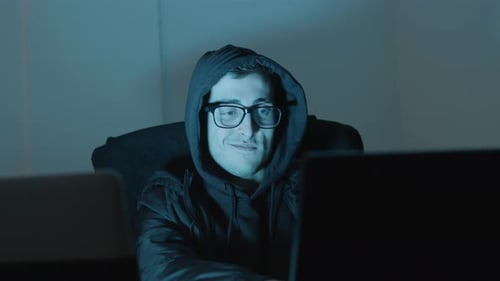 Smart Young Man in Hood Working on Laptop Late at Night