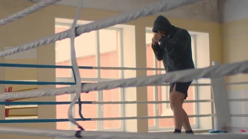 Hooded Man Shadow Boxing in a Boxing Ring