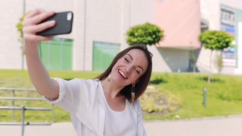 Woman with phone recording vlog or making video call on street.