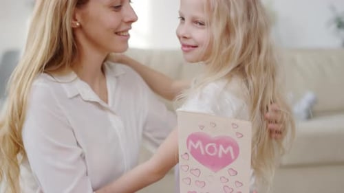 Loving Mother and Daughter Embrace with Handmade Card
