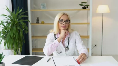 Senior European Woman Doctor Wearing White Medical Coat and Stethoscope Looking at Camera