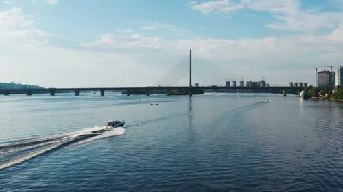 Aerial View of Motorboat Sailing on River on Background of Cityscape