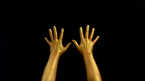 Schöne Aufnahmen von Frau Gold Hands Gesture. Schwarzer Hintergrund. Hände in Goldfarbe, Farbe auf Schwarz