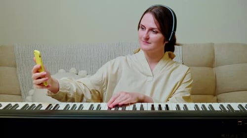 Woman Plays Keyboard While Looking at Phone