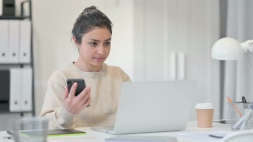 Young Woman Uses Phone at Office Desk