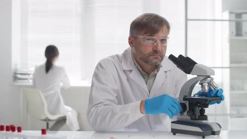 Scientist Adjusting Microscope in Bright Laboratory