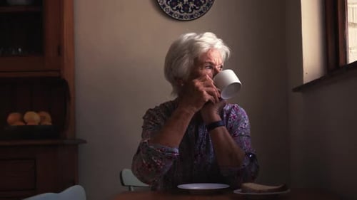 Senior Woman Drinking Tea by Window Indoors