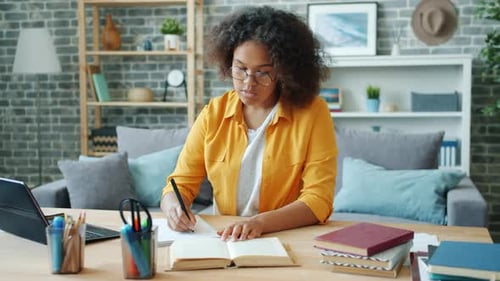 Woman Studying at Desk, Writing in Notebook
