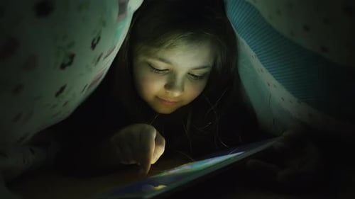 Une fille de dix ans utilise une tablette la nuit