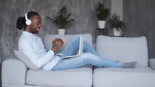 Man Video Chatting on Laptop While Lying on Couch